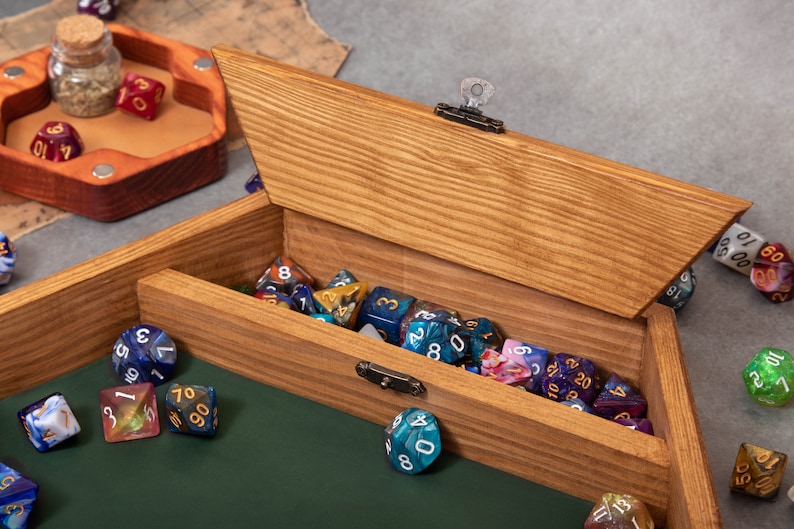 May include: A wooden box with a hinged lid, filled with colorful dice. The box has a lock and key. The dice are scattered on a green felt surface.