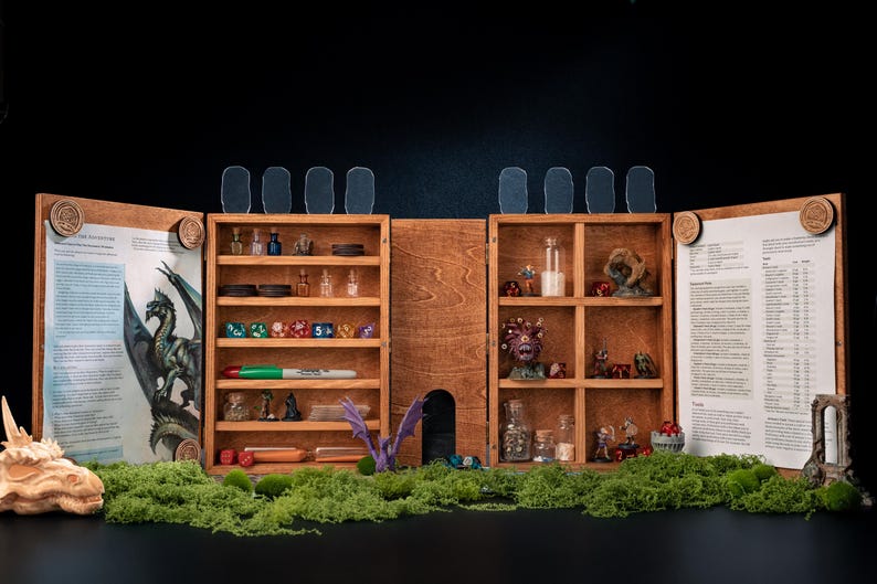 May include: A wooden tabletop gaming organizer with multiple shelves and compartments. It features dice, miniature figurines, and potion bottles. The organizer is open, revealing printed pages and a dragon sculpture, set against a black background.