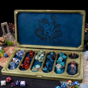 May include: A rectangular wooden dice storage box with a hinged lid featuring a black octopus and die graphic. The interior has blue felt-lined compartments holding various multi-coloured polyhedral dice and two small miniature figurines.