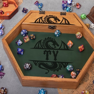 May include: A wooden hexagonal dice tray with a green felt interior. The tray has a dragon design and the name "TY" engraved on it. The tray is filled with colorful dice.