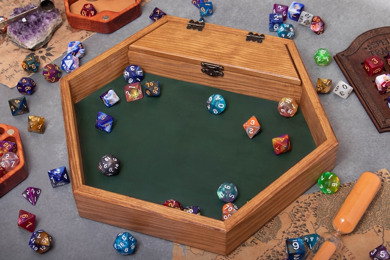May include: A wooden hexagonal dice tray with a green felt lining. The tray has a hinged lid and is filled with various colorful dice.