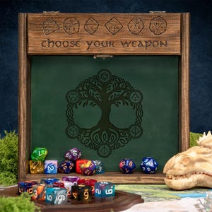 May include: Wooden dice display case with the text "choose your weapon". The case has a green interior with a tree of life design. Assorted colorful dice are displayed in front of the case, along with a dragon skull.