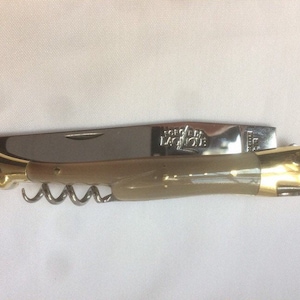 May include: A folding pocket knife with a bone handle, a corkscrew, and a blade. The knife is made by Forge de Laguiole.