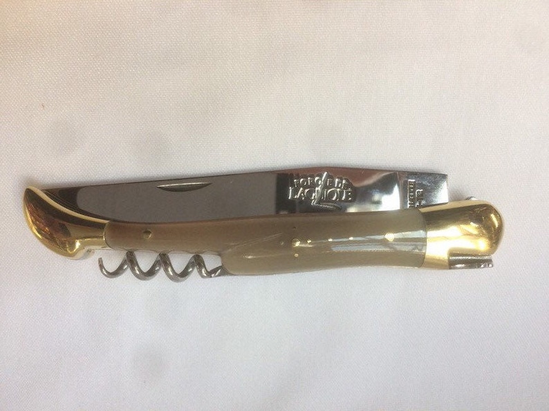 May include: A folding pocket knife with a bone handle, a corkscrew, and a blade. The knife is made by Forge de Laguiole.