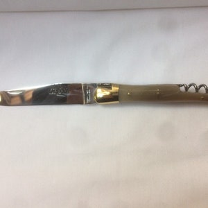 May include: A silver pocket knife with a brown handle and a corkscrew. The knife has a gold-colored metal accent on the handle.