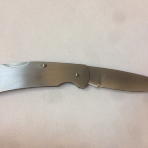 以下が含まれることがあります： 湾曲した刃と銀色のハンドルを持つ銀色のポケットナイフ。ナイフはシンプルなデザインで、閉じています。