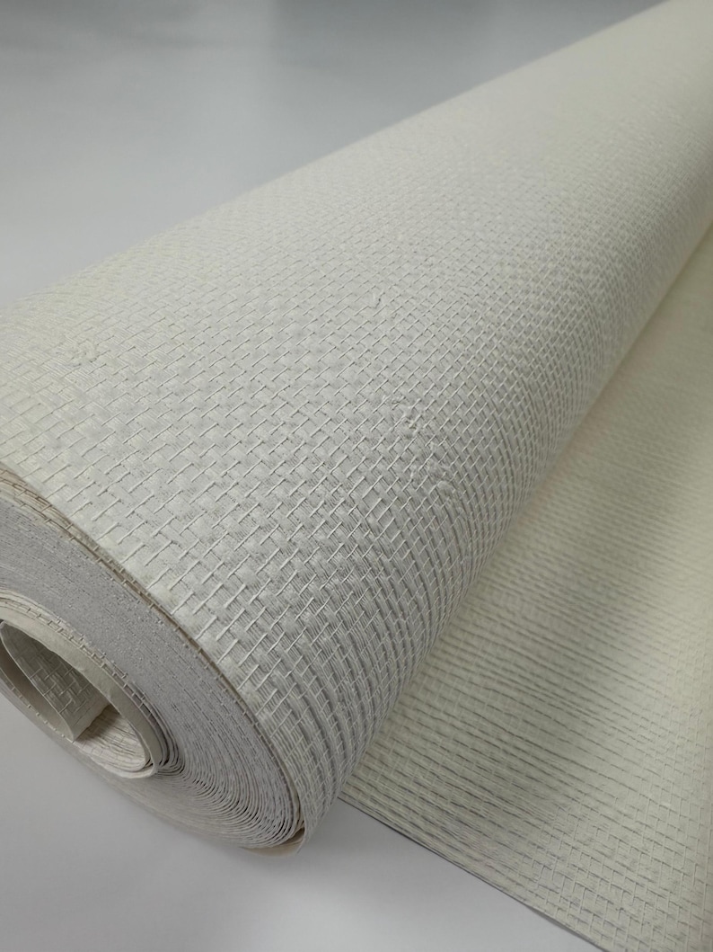 Puede incluir: Un rollo de papel tapiz blanco texturizado con un sutil patr&oacute;n de cuadr&iacute;cula. El papel tapiz est&aacute; enrollado y el extremo del rollo est&aacute; desenrollado, mostrando la textura y el patr&oacute;n.