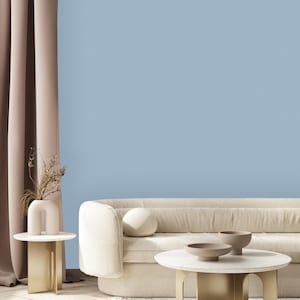 May include: A white, tufted sofa with a light blue wall behind it. A gold metal coffee table with a white marble top sits in front of the sofa. Two small, round, brown ceramic bowls are on the table.