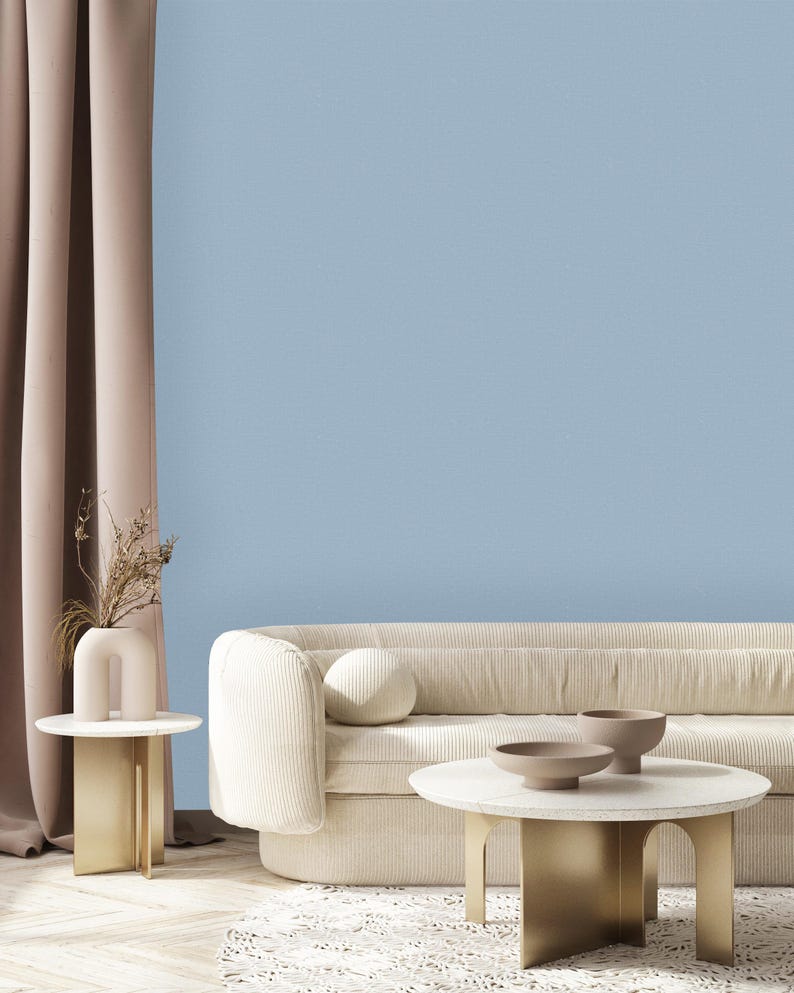 May include: A white, tufted sofa with a light blue wall behind it. A gold metal coffee table with a white marble top sits in front of the sofa. Two small, round, brown ceramic bowls are on the table.