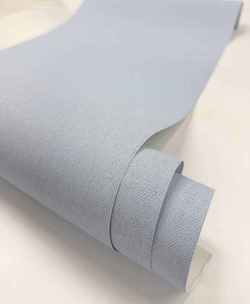 May include: A roll of light blue fabric with a textured surface.