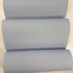 May include: A roll of light blue fabric. The fabric is smooth and has a subtle texture.