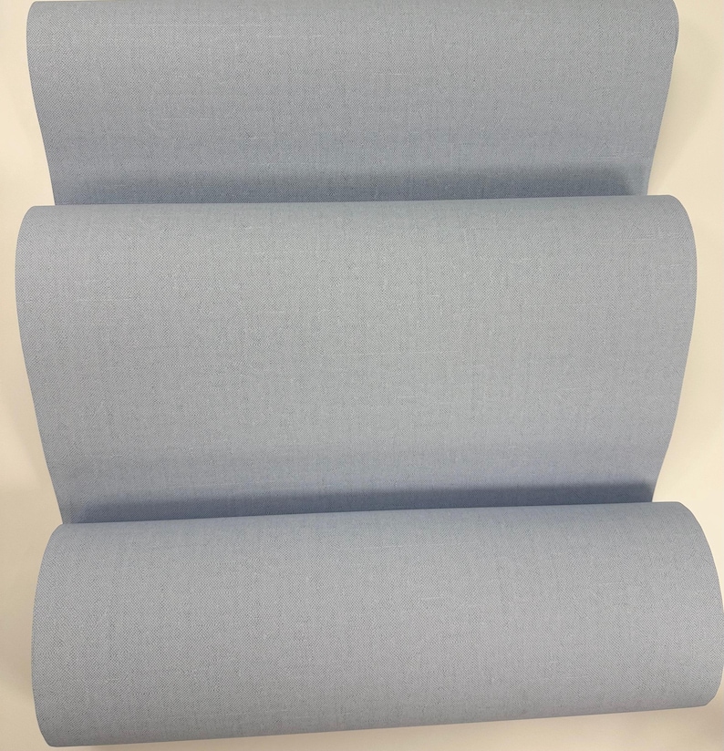 May include: A roll of light blue fabric. The fabric is smooth and has a subtle texture.