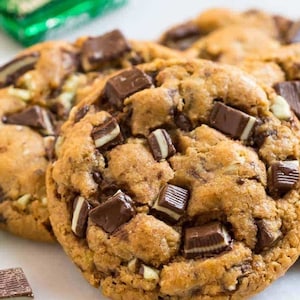 May include: Close-up of three chocolate chip cookies with mint chocolate chips. The cookies are golden brown and have a soft, chewy texture.