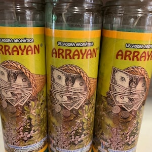 Puede incluir: Tres velas de vidrio verde en frascos con etiquetas amarillas y doradas. Las etiquetas dicen "Veladora Aromatica Arrayan" y muestran una imagen de dinero y monedas. Las velas son para uso espiritual o religioso.
