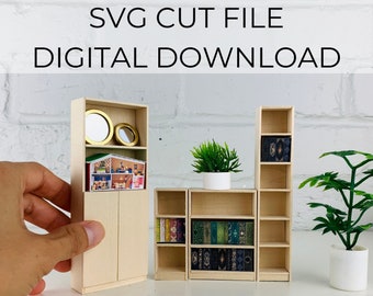 May include: A set of three miniature wooden bookcases in a 1:16 scale. The bookcases are all different sizes and have shelves for displaying books or other small items. The bookcases are made of light wood and have a natural finish. The set includes a tall bookcase with two doors, a shorter bookcase with open shelves, and a very small bookcase with two shelves. The set is labeled "Classic Bookcase Bundle".