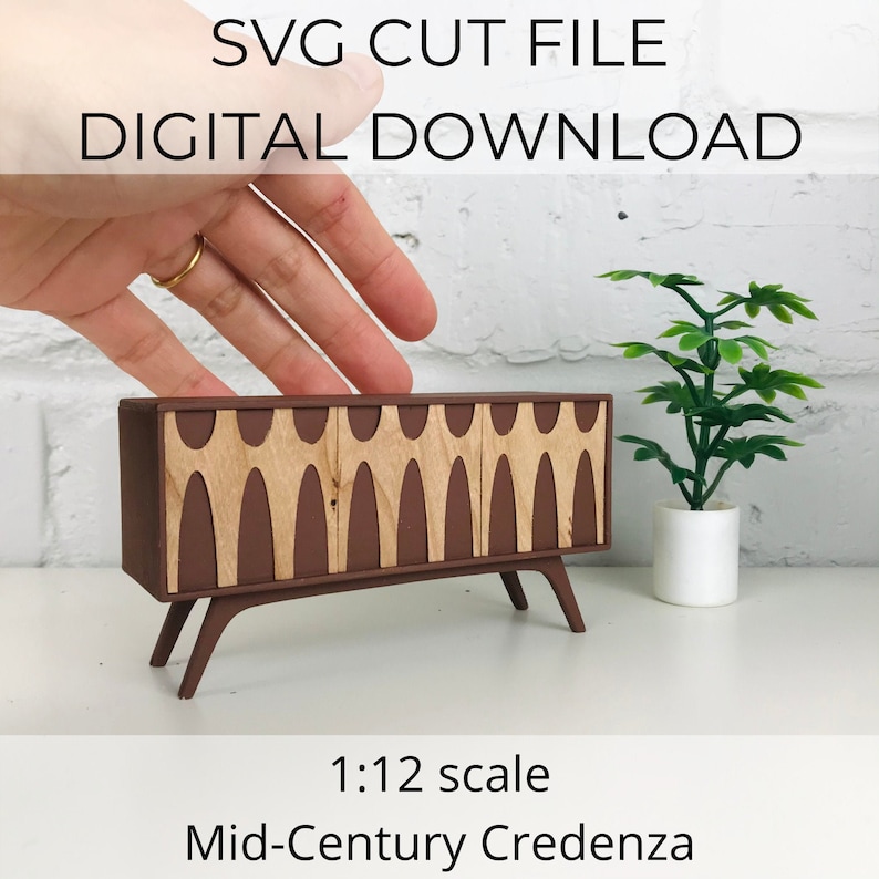 May include: A miniature mid-century modern credenza in a 1:12 scale. The credenza is brown with light wood-colored accents and angled legs. The image includes the text "SVG CUT FILE DIGITAL DOWNLOAD".