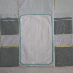 Peut inclure: Un matelas &agrave; langer gris et blanc avec une bordure bleu clair et une fermeture &eacute;clair dor&eacute;e. Le matelas &agrave; langer a une petite poche sur le c&ocirc;t&eacute; avec le texte "Little de Paris" imprim&eacute; dessus.