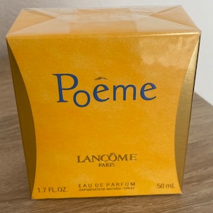 Könnte beinhalten: Eine rechteckige, goldgelbe Parfümbox mit dem Wort „Poême“ in blauer Schrift. Die Box trägt auch den Markennamen „Lancôme Paris“ und den Text „Eau de Parfum“ und „1,7 fl. oz. 50 ml“.