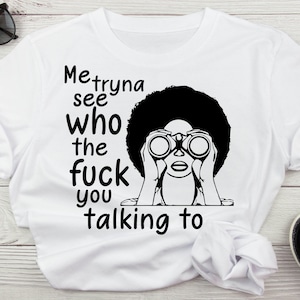 May include: White t-shirt with a black graphic of a person looking through binoculars and the text "Me tryna see who the fuck you talking to". Black sunglasses and sandals are visible.