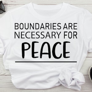 May include: White t-shirt with black text that reads "Boundaries are necessary for peace".