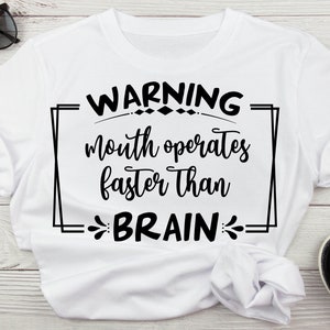 May include: White t-shirt with black text that reads "WARNING mouth operates faster than BRAIN" in a decorative frame.