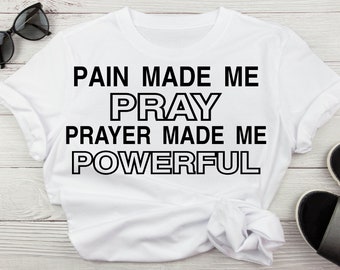 Könnte beinhalten: Weißes T-Shirt mit schwarzem Text, der "Pain made me pray, prayer made me powerful." lautet.