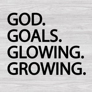 以下が含まれることがあります： 白い木製の背景に黒い文字で「GOD. GOALS. GLOWING. GROWING.」と書かれています