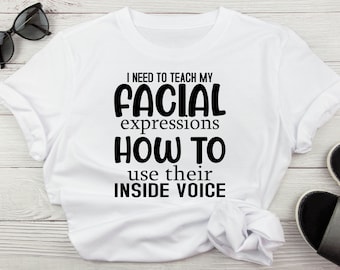 May include: White t-shirt with black text that reads "I need to teach my facial expressions how to use their inside voice."
