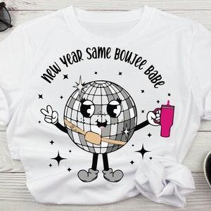Może przedstawiać: Biała koszulka z czarno-białym nadrukiem dyskotekowej kuli i tekstem "new year same boujee babe".