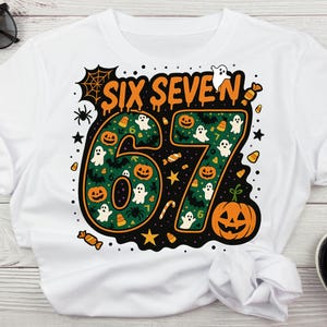Può includere: T-shirt bianca con un design a tema Halloween. La scritta arancione "SIX SEVEN" adorna il davanti, con i numeri "67" riempiti di fantasmi, zucche e caramelle. Un ragno, stelle e una zucca completano il design.