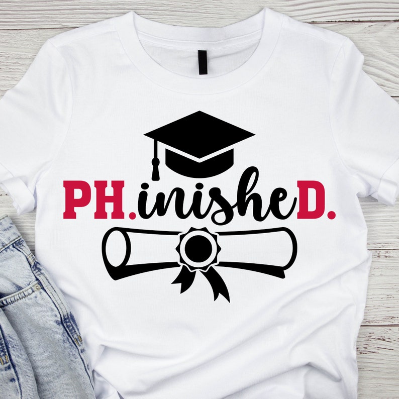 以下が含まれることがあります： 黒い卒業帽と卒業証書、そして「PH.inished.」という赤い文字と黒い文字が書かれた白いTシャツです。