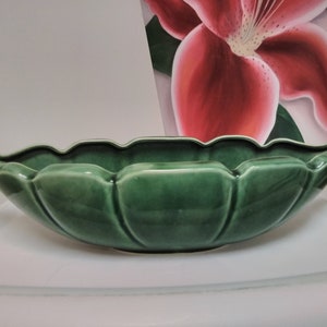 May include: A green ceramic bowl shaped like a leaf with scalloped edges and a smooth, glossy finish.