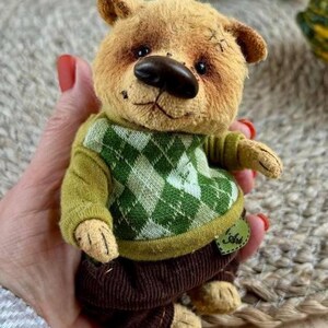 May include: Adorable handmade teddy bear, light brown fur, green checkered sweater, brown corduroy pants.  It has worn details for a vintage look.  The bear is dressed in a green sweater and brown pants, the clothes can be removed.  The bear's nose is dark brown. The bear is approximately 6 inches tall.
