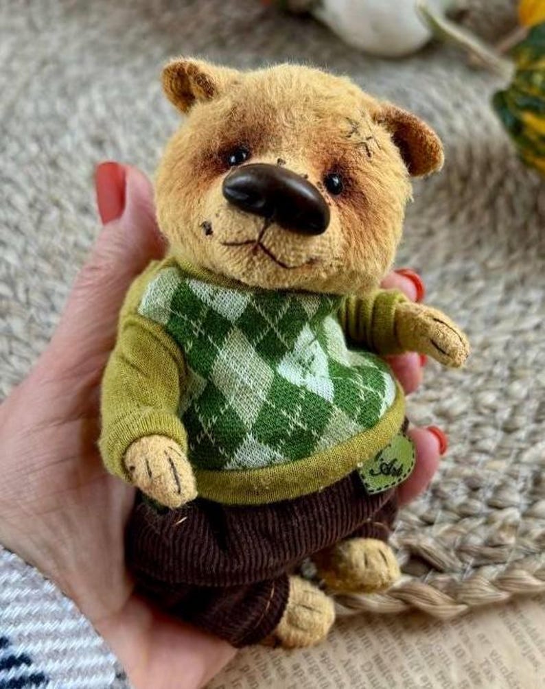 May include: Adorable handmade teddy bear, light brown fur, green checkered sweater, brown corduroy pants.  It has worn details for a vintage look.  The bear is dressed in a green sweater and brown pants, the clothes can be removed.  The bear's nose is dark brown. The bear is approximately 6 inches tall.