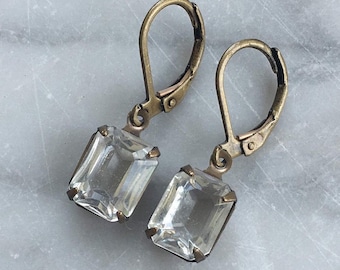 May include: A pair of gold-tone dangle earrings with clear rectangular crystal stones.