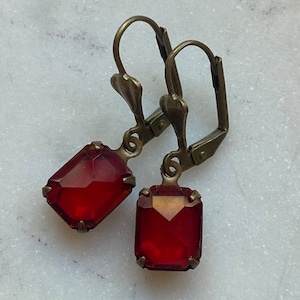 May include: A pair of earrings with red gemstone accents and antique brass hooks.