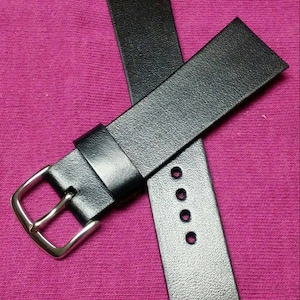 Könnte beinhalten: Ein schwarzes Lederarmband mit einer silbernen Schließe. Das Armband hat fünf Löcher zum Einstellen der Größe.