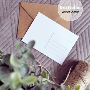 May include: A blank white postcard with a brown envelope and twine on a purple textured background. The postcard has lines for an address and a space for a stamp. The text "Bestseller print card" is on a white circle.