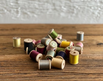 Lot of 33 vintage wooden spools or bobbins with their colorful thread, circa 1950s