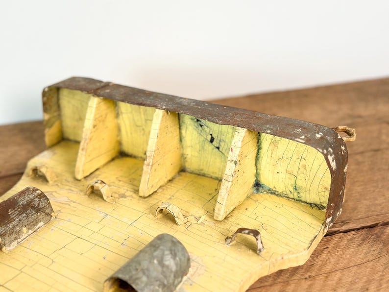 K&ouml;nnte beinhalten: Eine verwitterte Holzkiste mit gelb lackiertem Innenraum und rostiger Metallau&szlig;enseite. Die Kiste hat mehrere F&auml;cher und eine kleine Schlaufe an der Seite. Die Farbe ist rissig und verleiht ihr ein rustikales Aussehen.