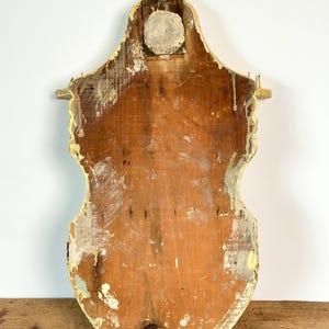 K&ouml;nnte beinhalten: Ein Vintage-Wandregal aus Holz mit einem abgenutzten, gealterten Aussehen. Das Regal ist mit einem verblichenen gelben Rand bemalt und hat eine nat&uuml;rliche Holzoberfl&auml;che. Die R&uuml;ckseite des Regals ist sichtbar und zeigt die Konstruktion und Abnutzung.