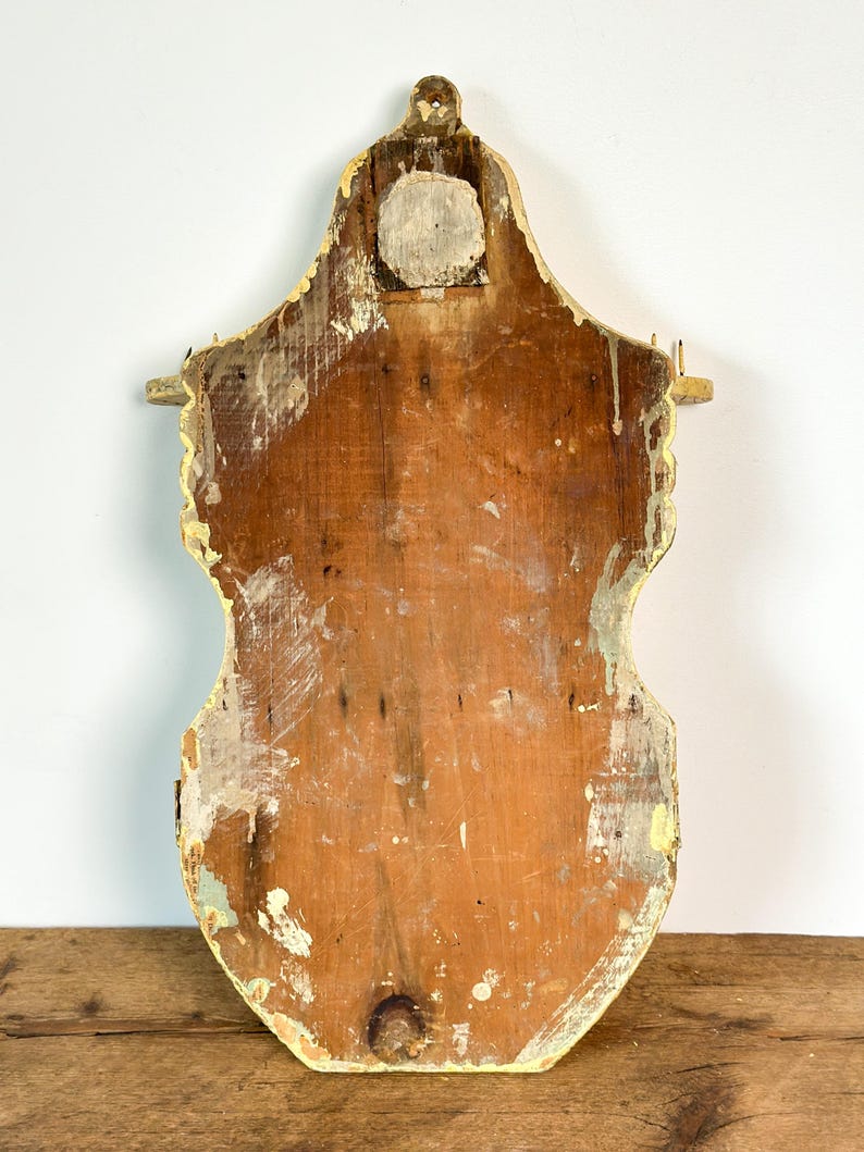 K&ouml;nnte beinhalten: Ein Vintage-Wandregal aus Holz mit einem abgenutzten, gealterten Aussehen. Das Regal ist mit einem verblichenen gelben Rand bemalt und hat eine nat&uuml;rliche Holzoberfl&auml;che. Die R&uuml;ckseite des Regals ist sichtbar und zeigt die Konstruktion und Abnutzung.