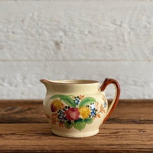 Vintage hand-painted ceramic milk jug or pitcher, beige with colorful floral designs, made in Japan