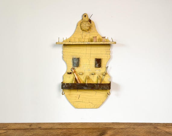Antique sewing tool and bobbin holder: wall mounted with pegs, shelf and old distressed yellow paint, circa 1920s