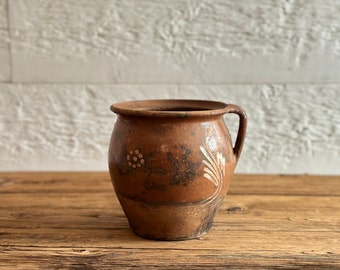 Antique terra cotta jar, with hand-painted white flowers, likely from South America in the 1930s