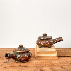 Puede incluir: Juego de tres tazas de cerámica con acabado mate moteado. Las tazas son de color crema, gris claro y gris oscuro. Diseño sencillo y minimalista, ideal para café o té.