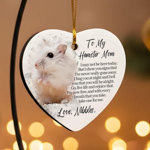Può includere: Ornamento a forma di cuore con l'immagine di un criceto e la scritta "To My Hamster Mom". L'ornamento bianco ha un bordo nero ed è sospeso da un filo d'oro. Il testo include una poesia e la firma "Love, Nibbles."