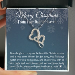 May include: A silver necklace with two interlocking heart pendants, encrusted with small, clear crystals. The necklace is presented in a gift box with a blue background and the text "Merry Christmas From Your Dad In Heaven."
