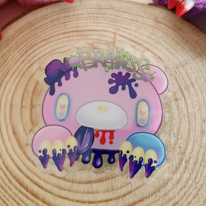 May include: A pink bear with purple and yellow claws, dripping with purple and blue paint. The bear has a white face with pink cheeks and blue eyes. The text "BRAINS" is written in green and purple letters above the bear.