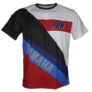 May include: White, black, red, and blue short-sleeved t-shirt with a diagonal stripe design. The shirt features the text "FZR" and "YAMAHA" in a bold, stylized font.